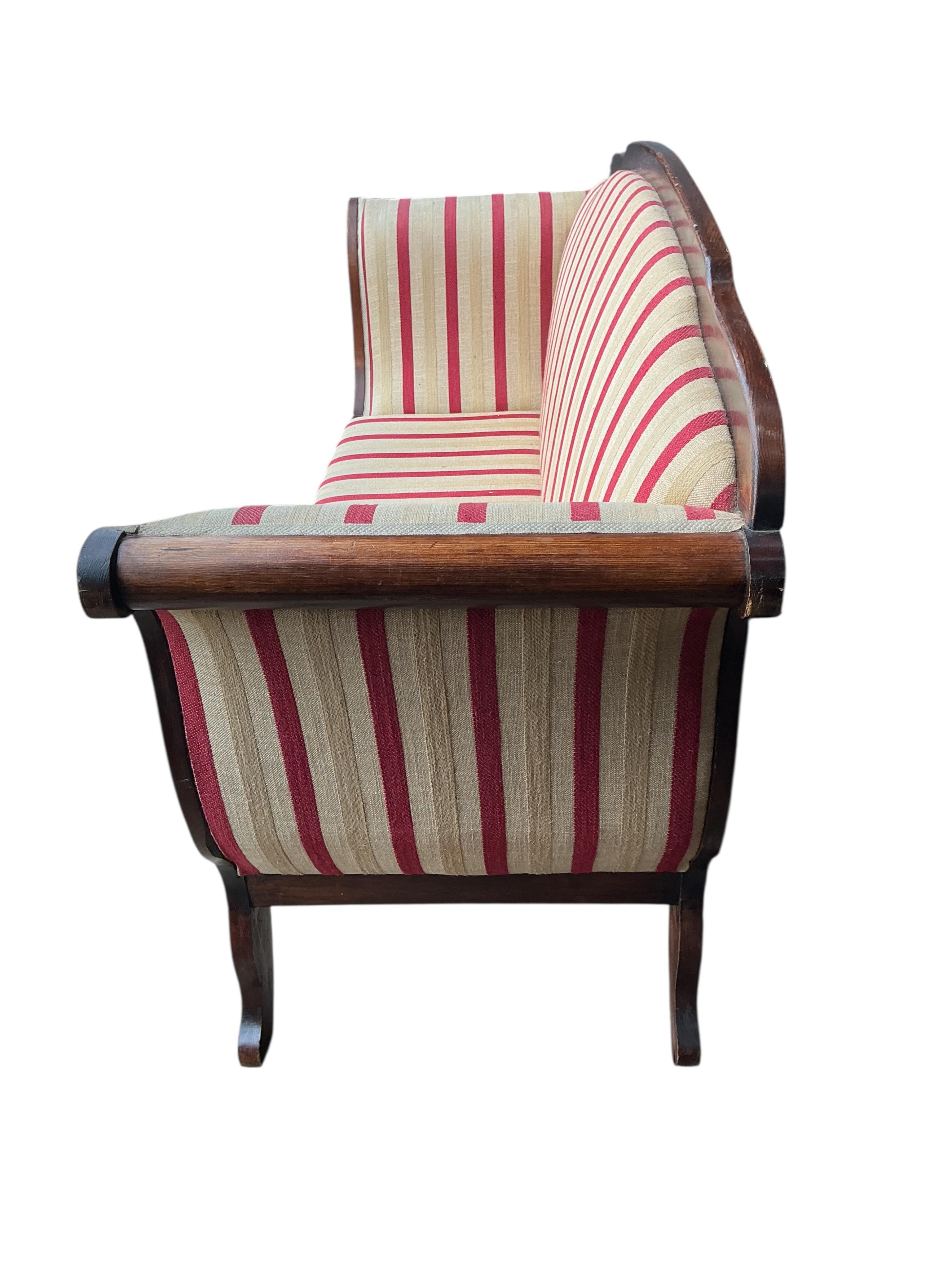 An early 19th century Continental pine scroll arm settee, width 190cm, depth 62cm, height 103cm